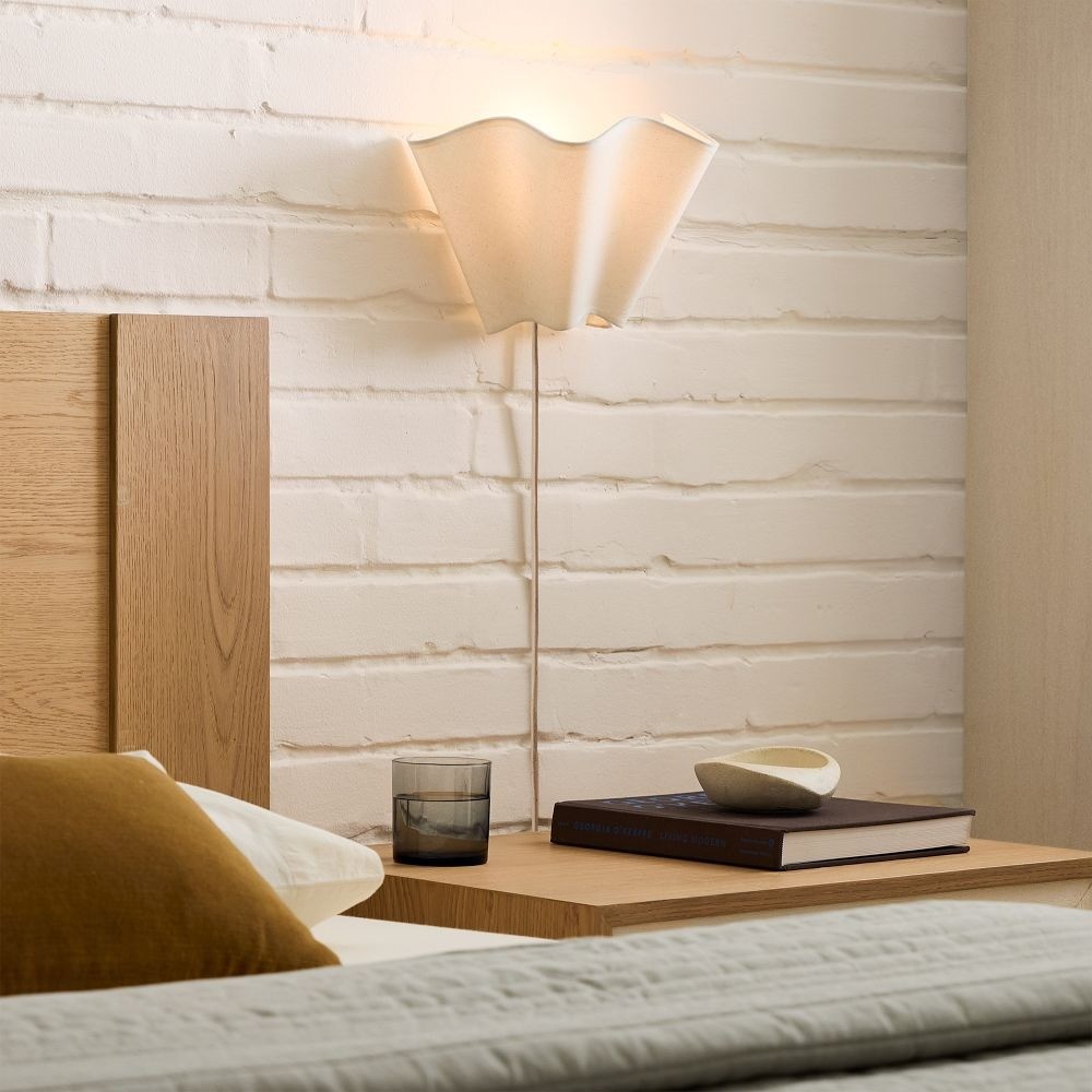 Aplique de pared Oslan sobre una mesita de noche en el dormitorio.
