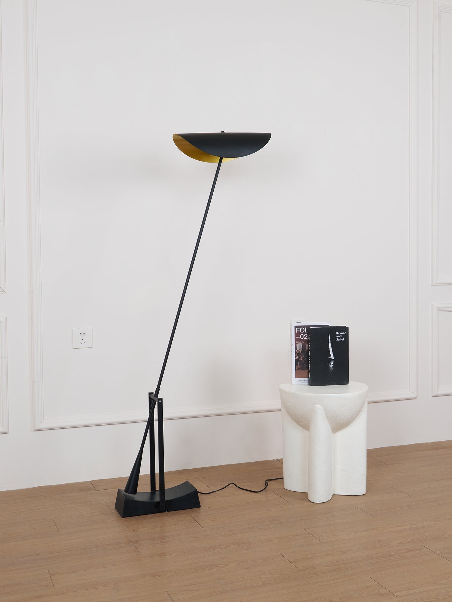 Pochylona czarna lampa podłogowa w pobliżu stołka