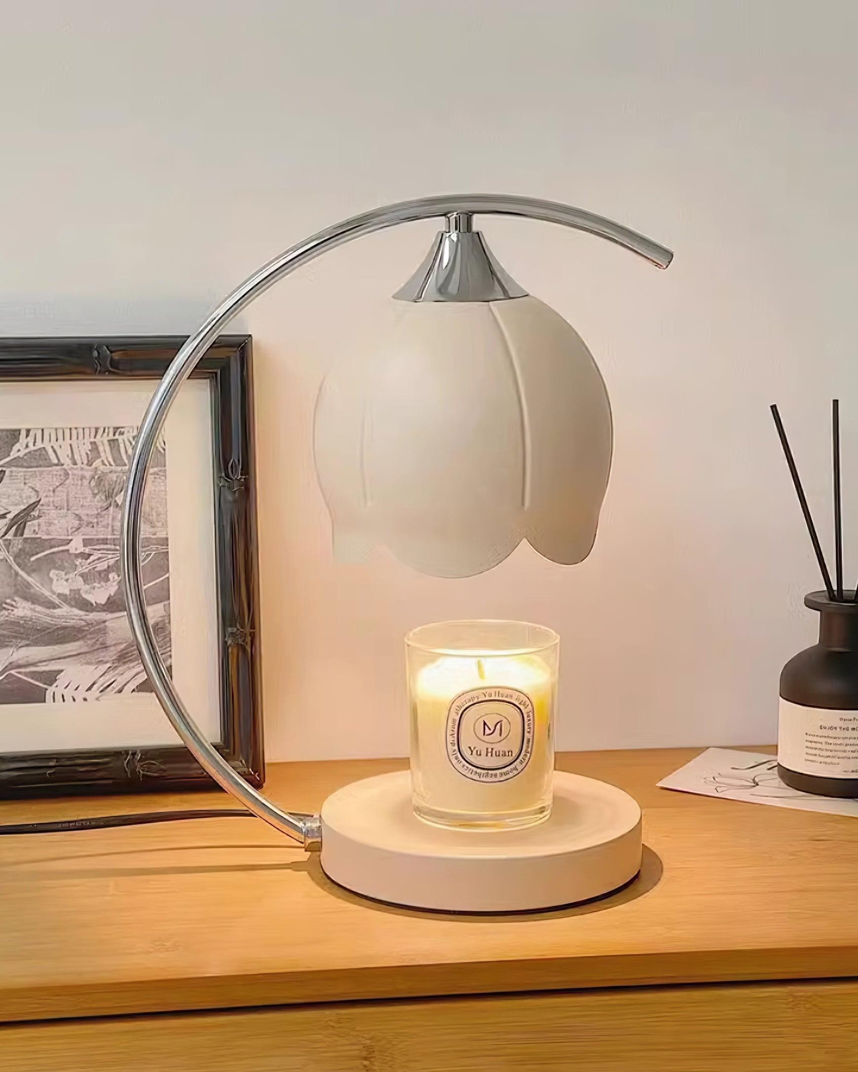 Lampa podgrzewająca świecę z chromowaną ramką w ciepłej scenie na blacie