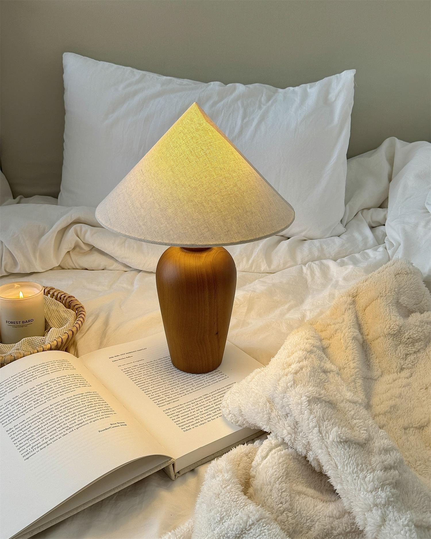 Lampa Braydena zapalona w pobliżu miękkiej pościeli i otwartej książki