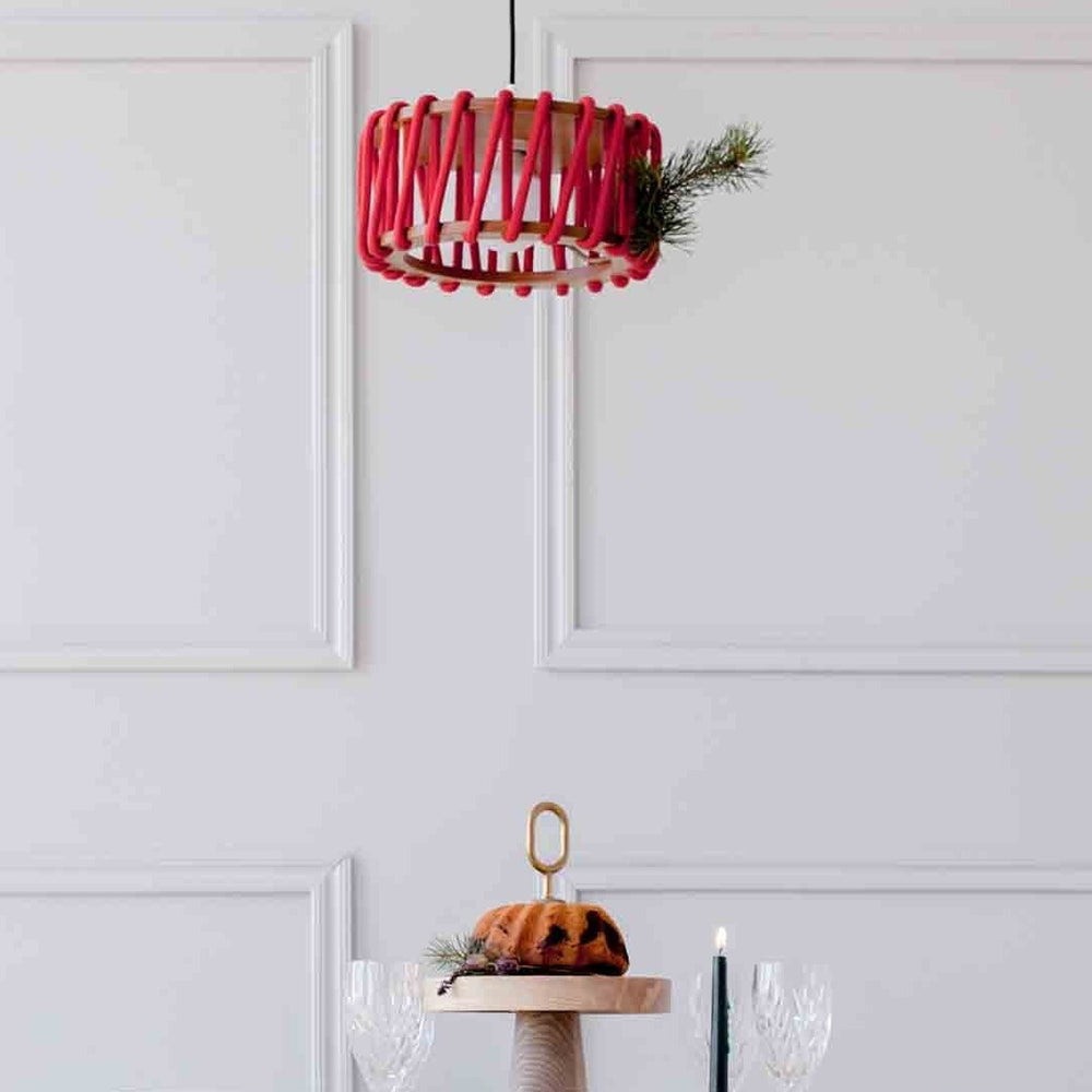 Röd Macaron-hänglampa installerad ovanför ett bord