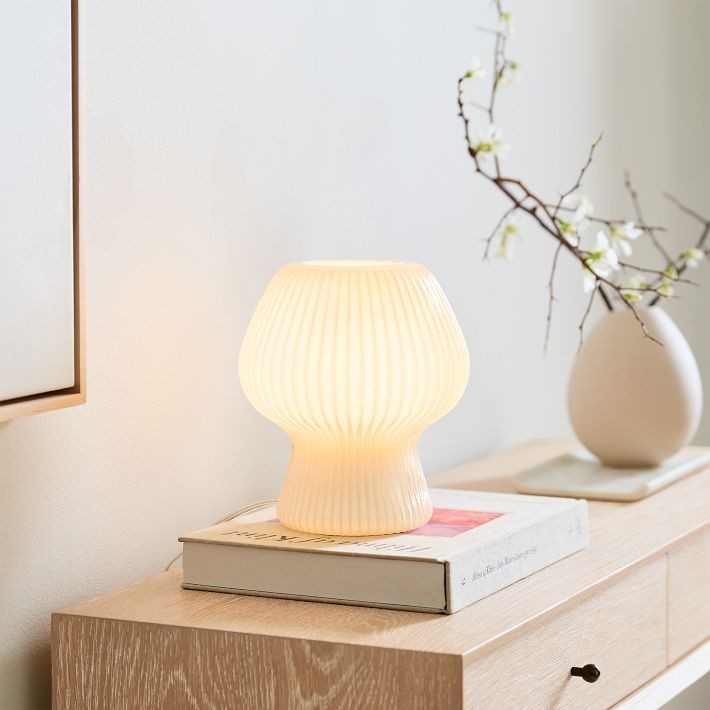 Ribbad glasbordslampa på böcker med vas och väggdekor