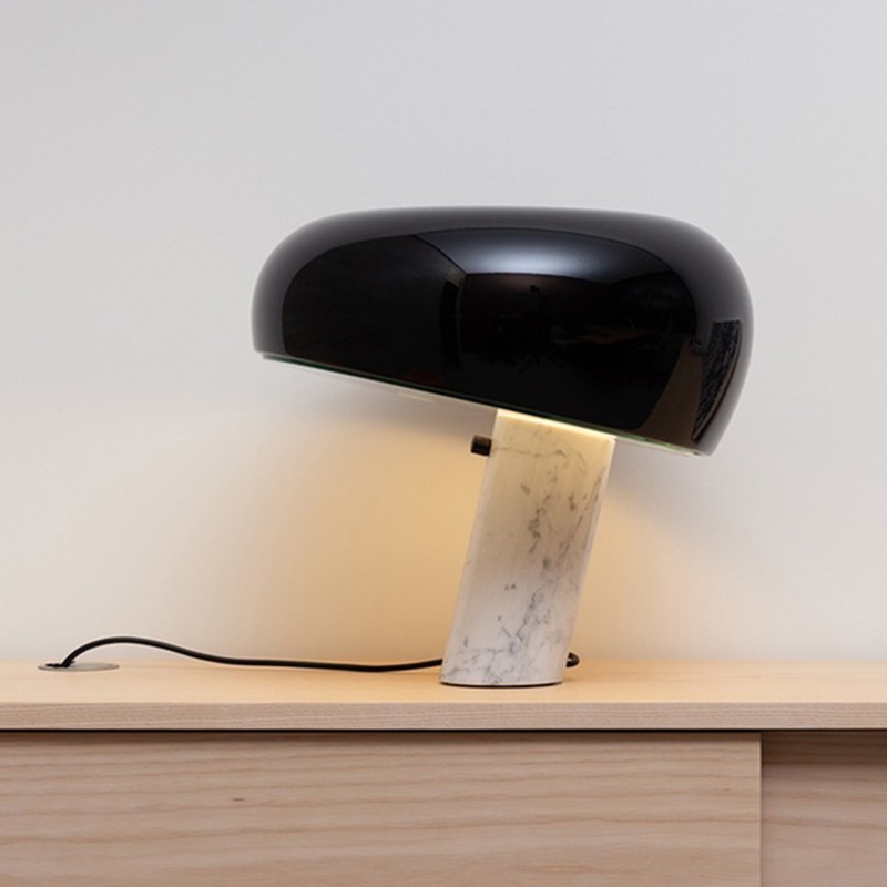 Lámpara de mesa curva de mármol negro iluminada sobre una consola