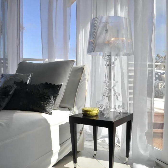 Clear Bourgie lamp beside sofa and window