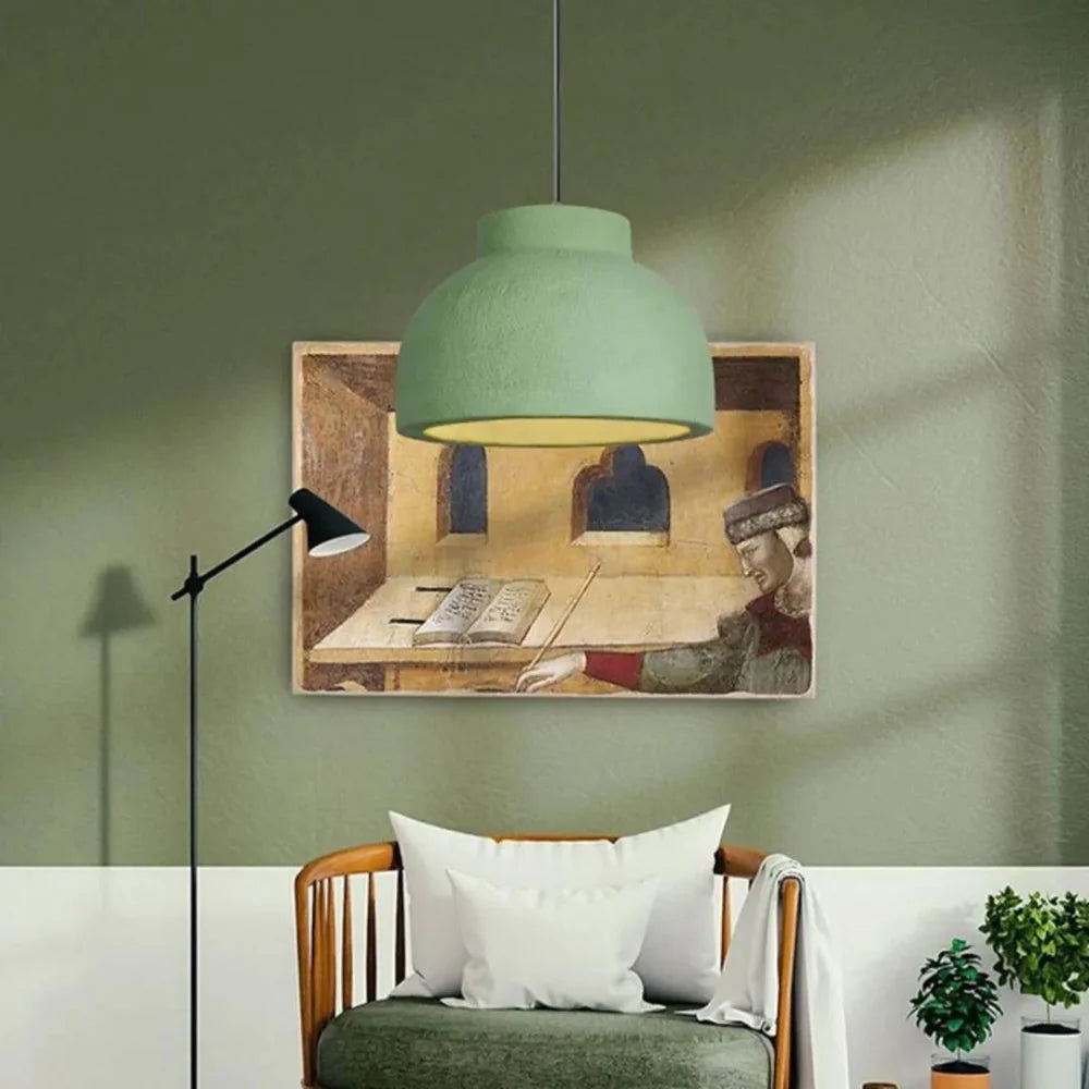 Lámpara colgante verde sobre los asientos en una habitación decorada.
