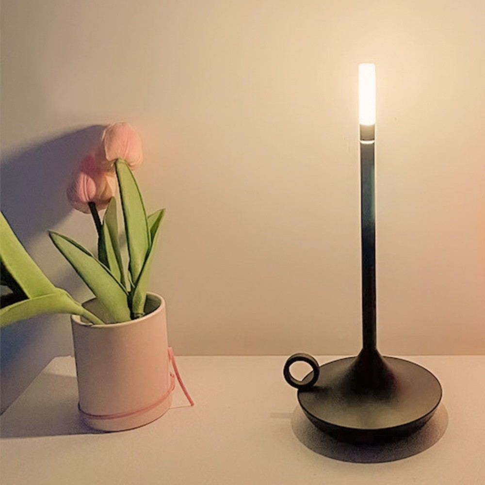 Czarna lampa S183 zapalona obok rośliny na blacie