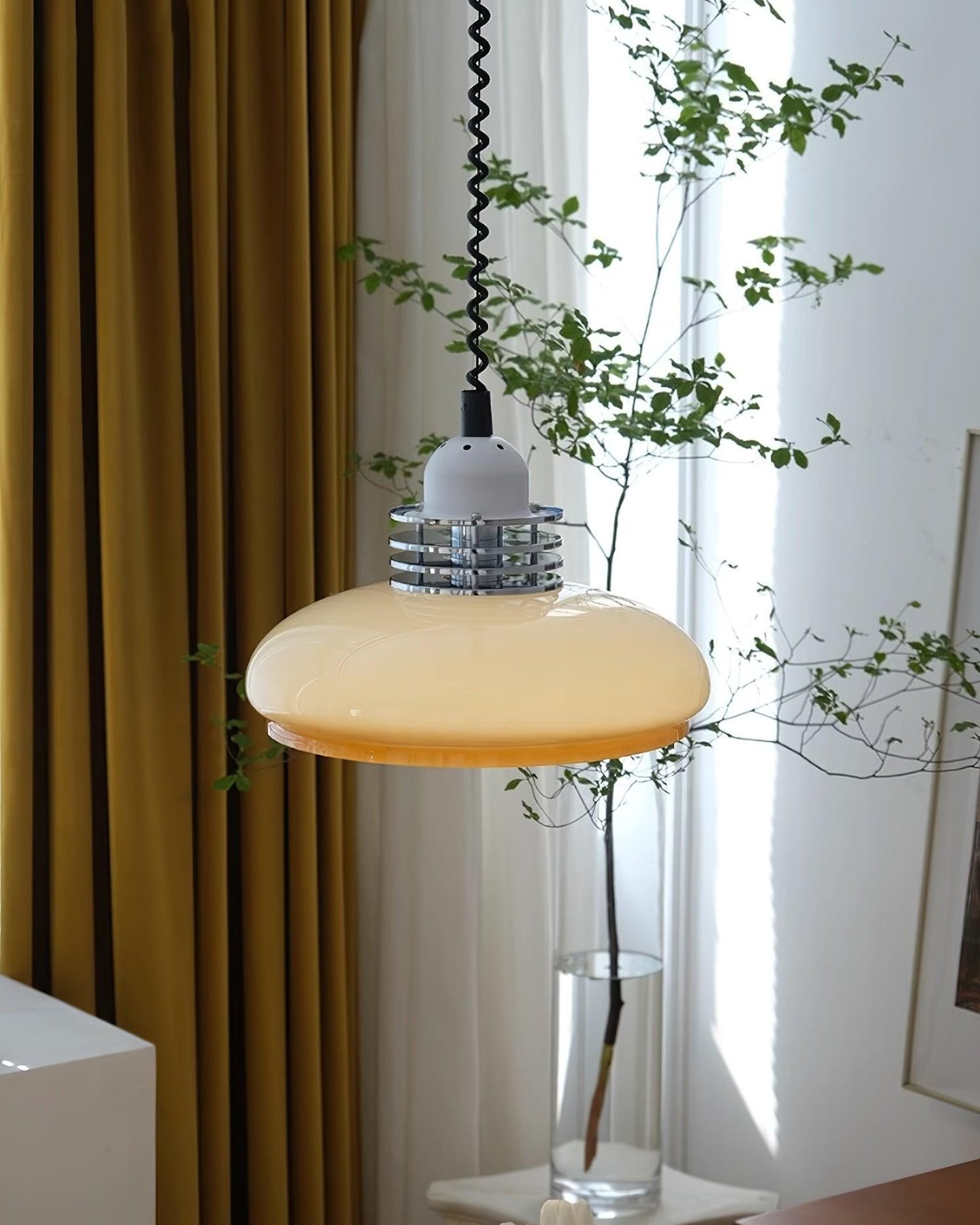 Lampa wisząca umieszczona w pobliżu zasłon i rośliny