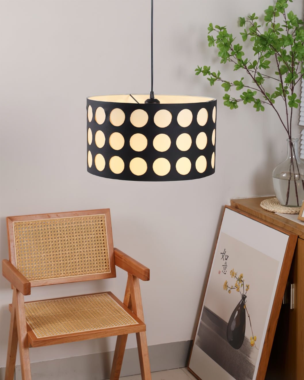 Lampa wisząca oświetlana nad krzesłem i oprawiona w ramkę grafika ścienna