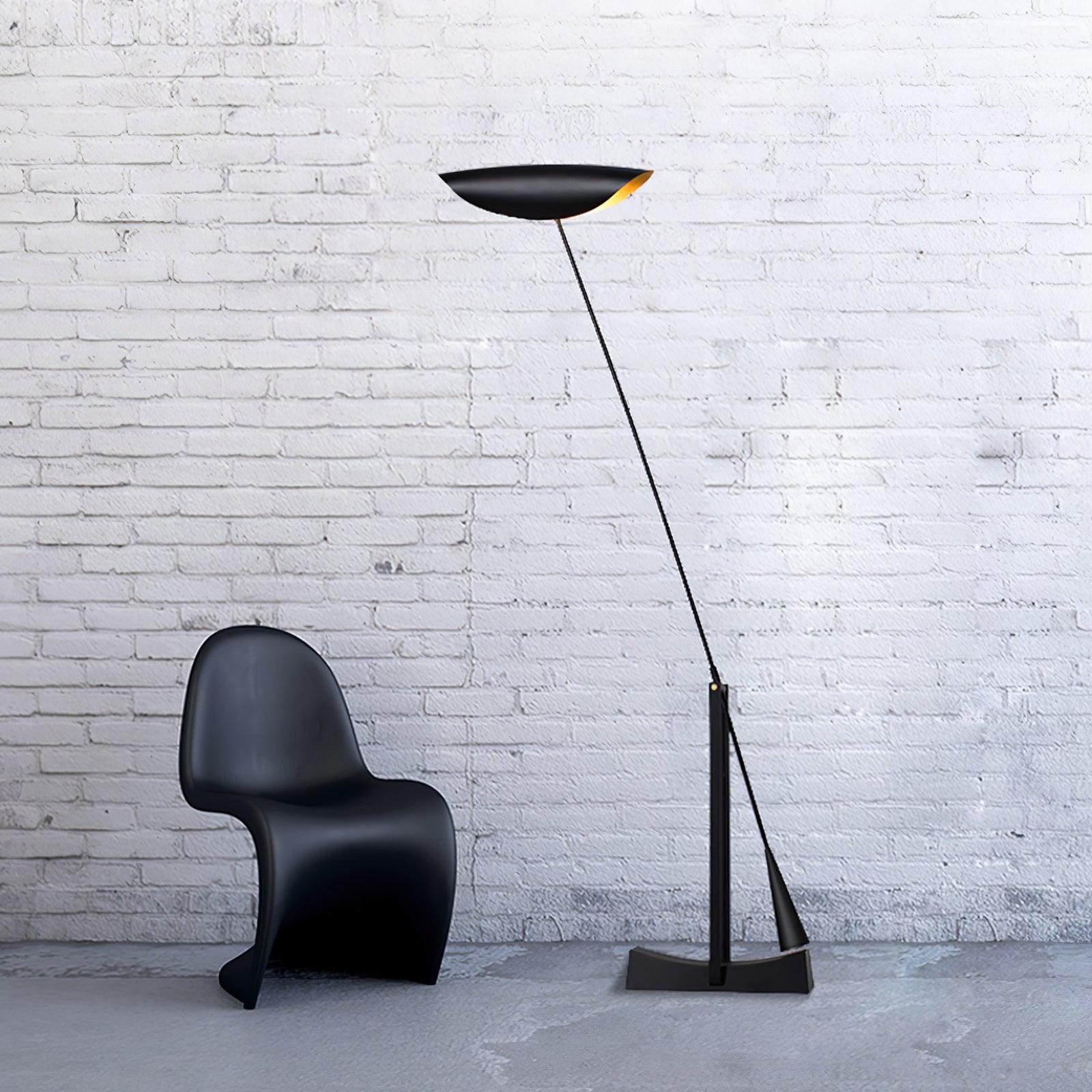 Pochylona lampa podłogowa obok krzesła przy ceglanej ścianie