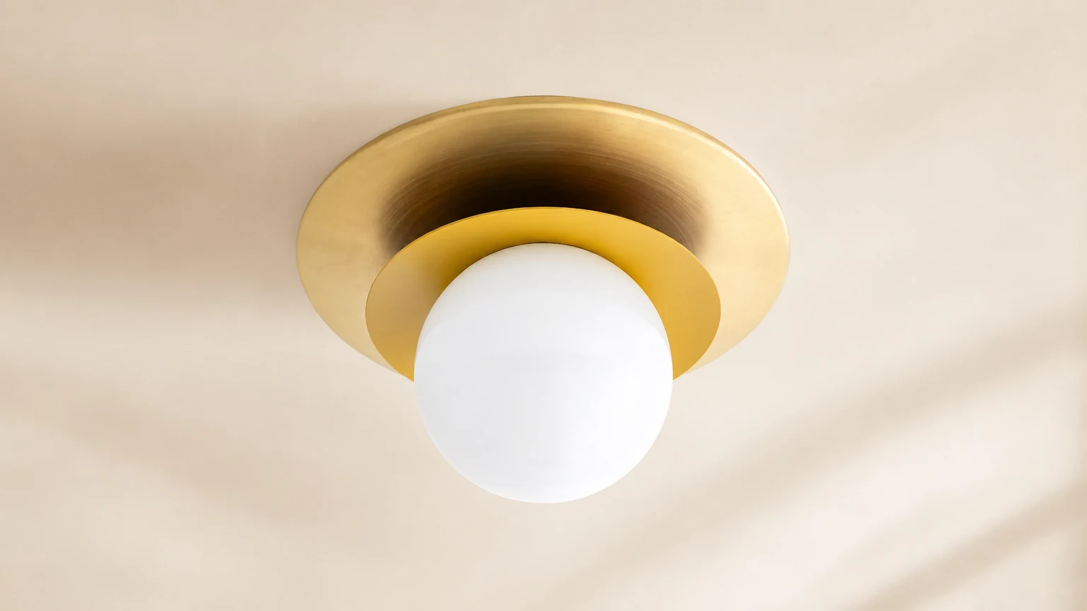 Warstwowa mosiężna lampa sufitowa Artivo zainstalowana w ciepłym, nowoczesnym pomieszczeniu