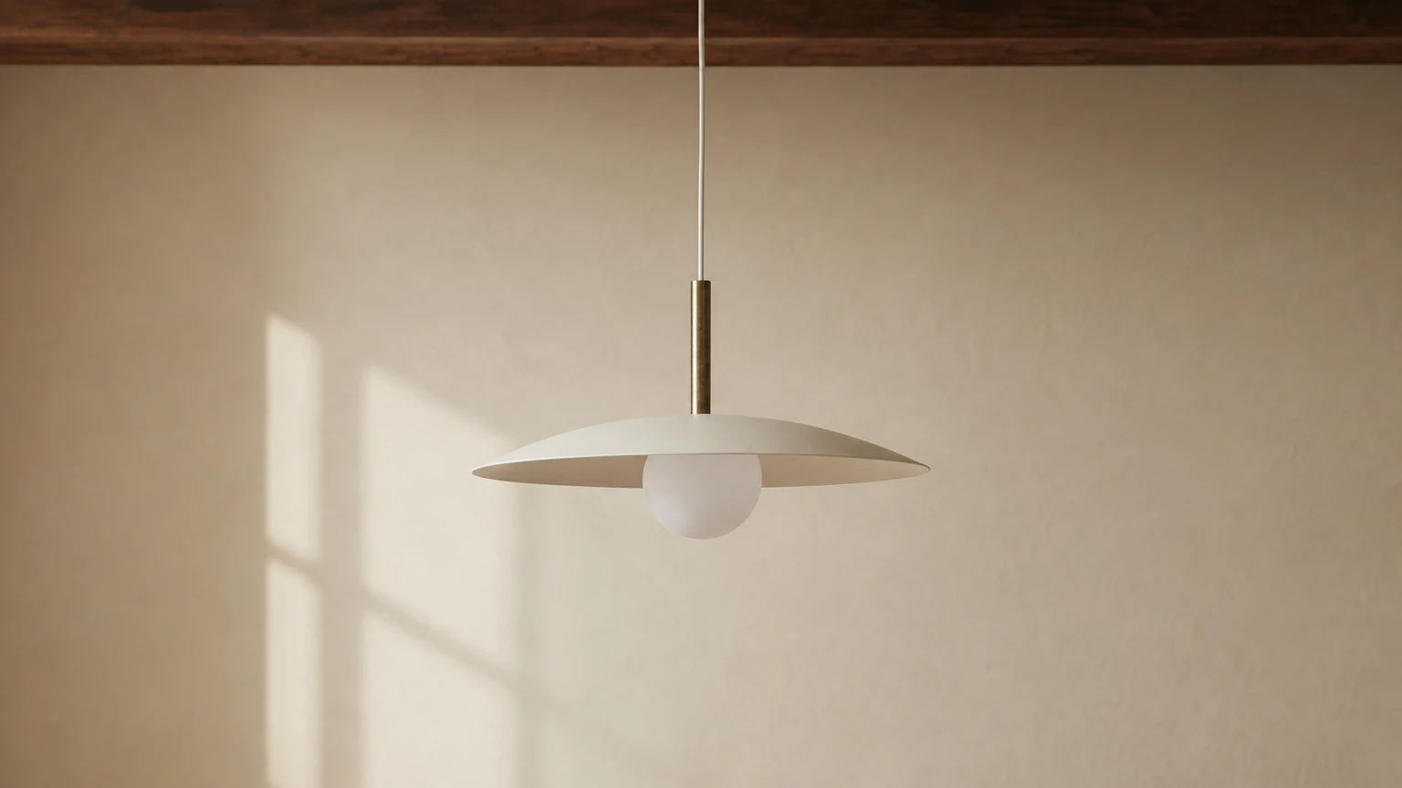 Mosiężna lampa wisząca Curva z akcentującym kloszem w ciepłym, nowoczesnym wnętrzu