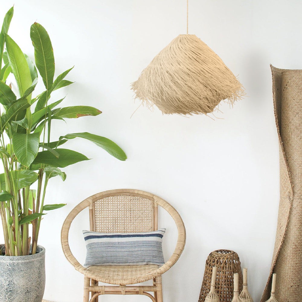 Rattanowa lampa wisząca w pokoju boho z krzesłem i roślinami