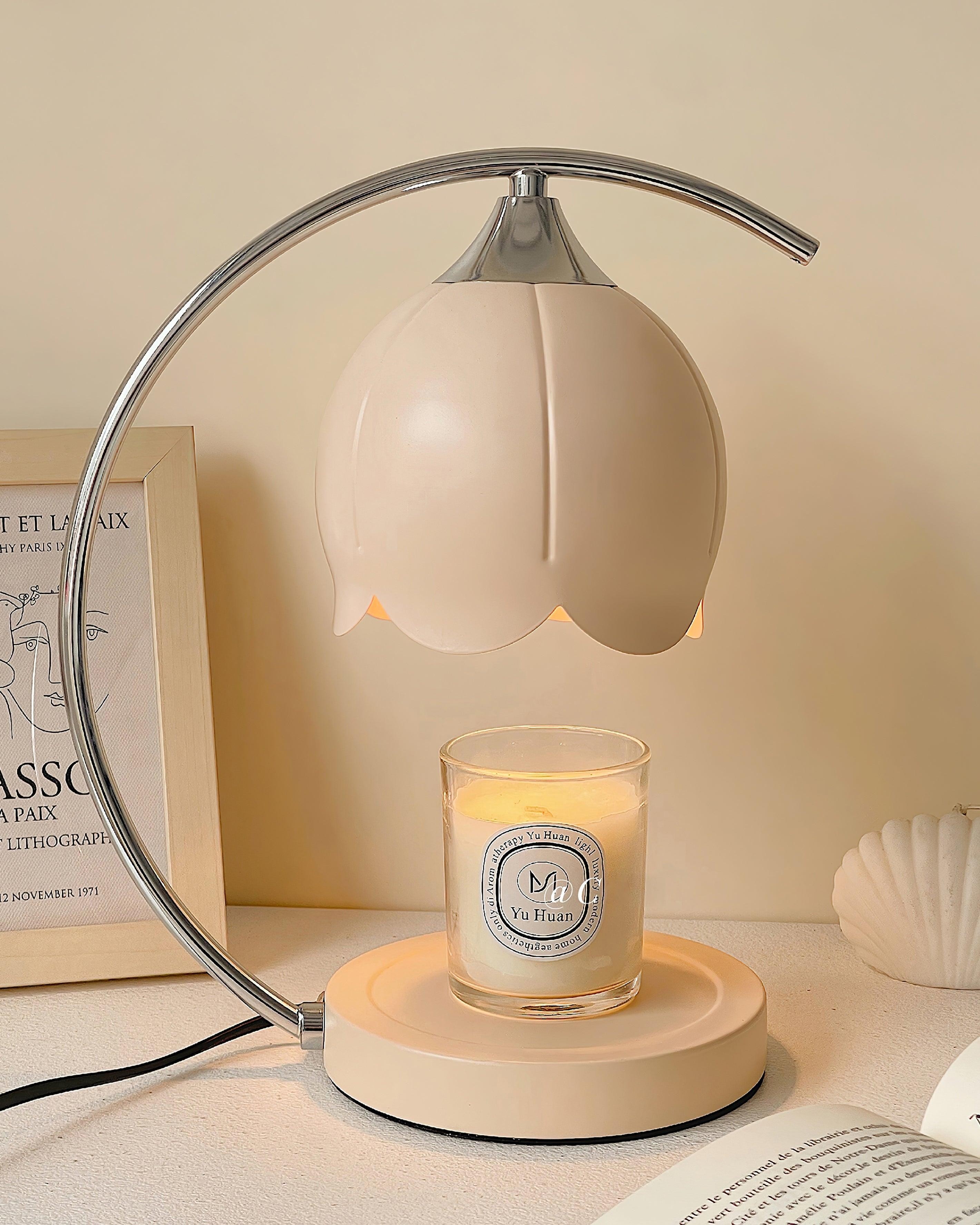 Lampa podgrzewająca świecę w srebrnej ramce na blacie z zapaloną świecą
