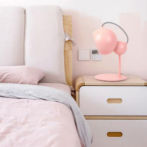 Rosa kugelförmige Tischlampe auf einem Nachttisch im Schlafzimmer