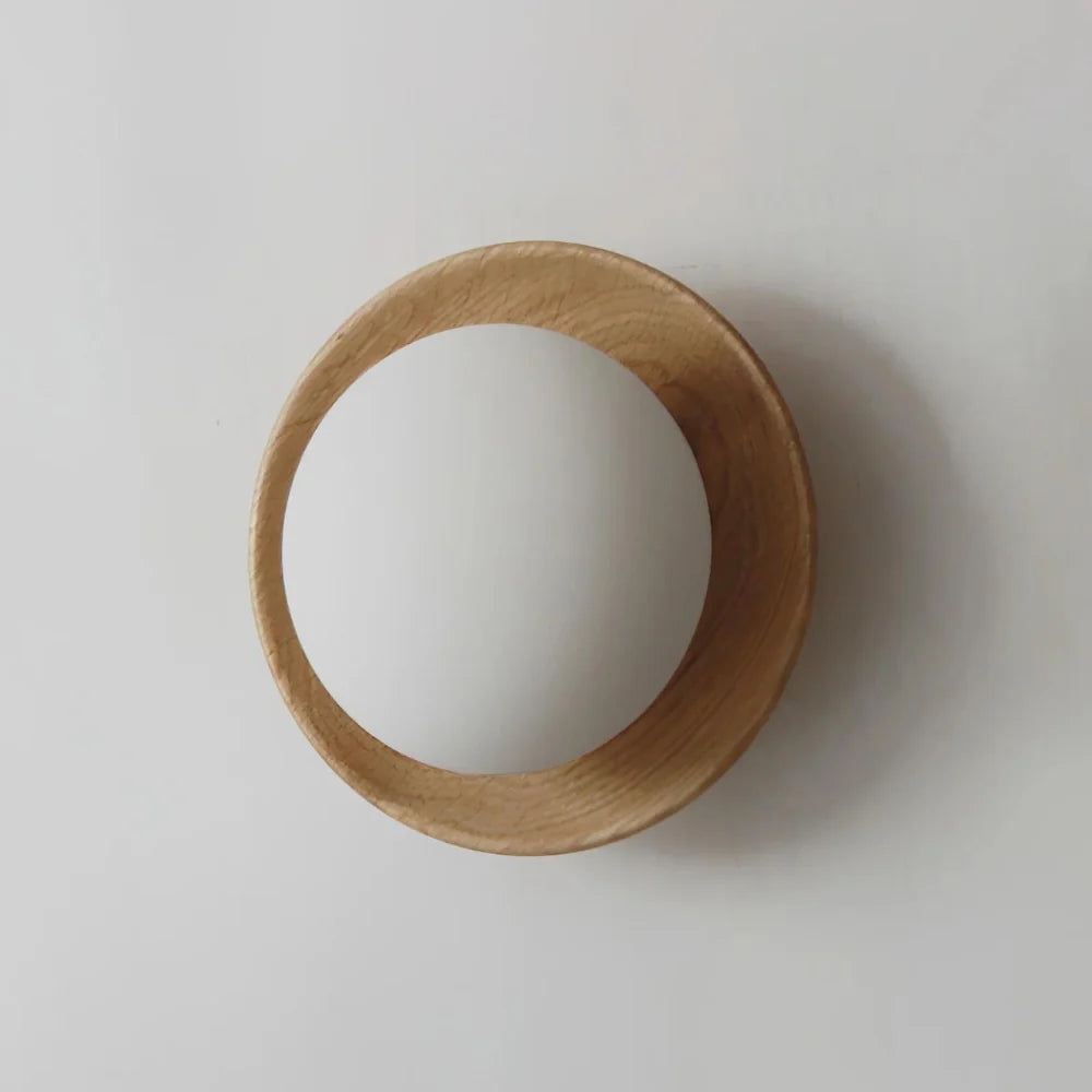 Aplique de pared de madera natural que proyecta una suave sombra en la pared.