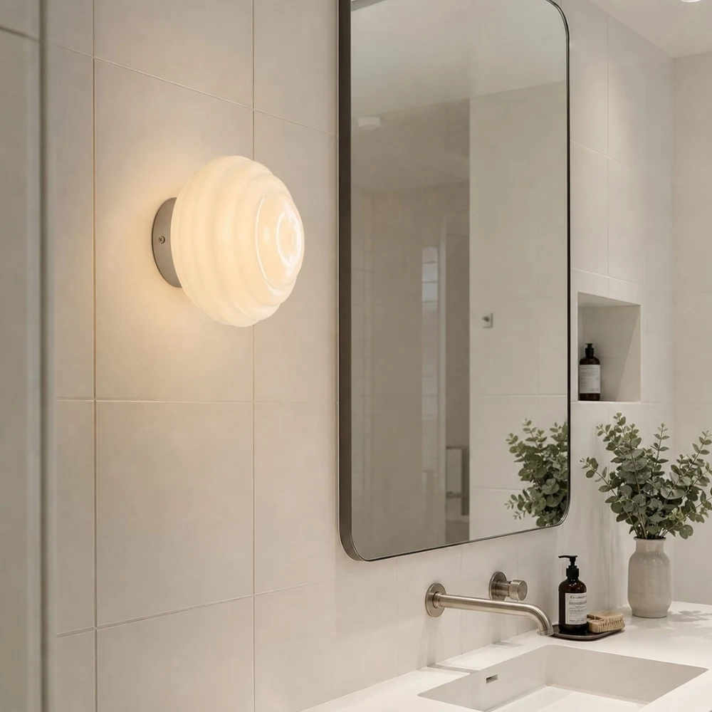 Cream ribbed glass wall sconce near a bathroom vanity