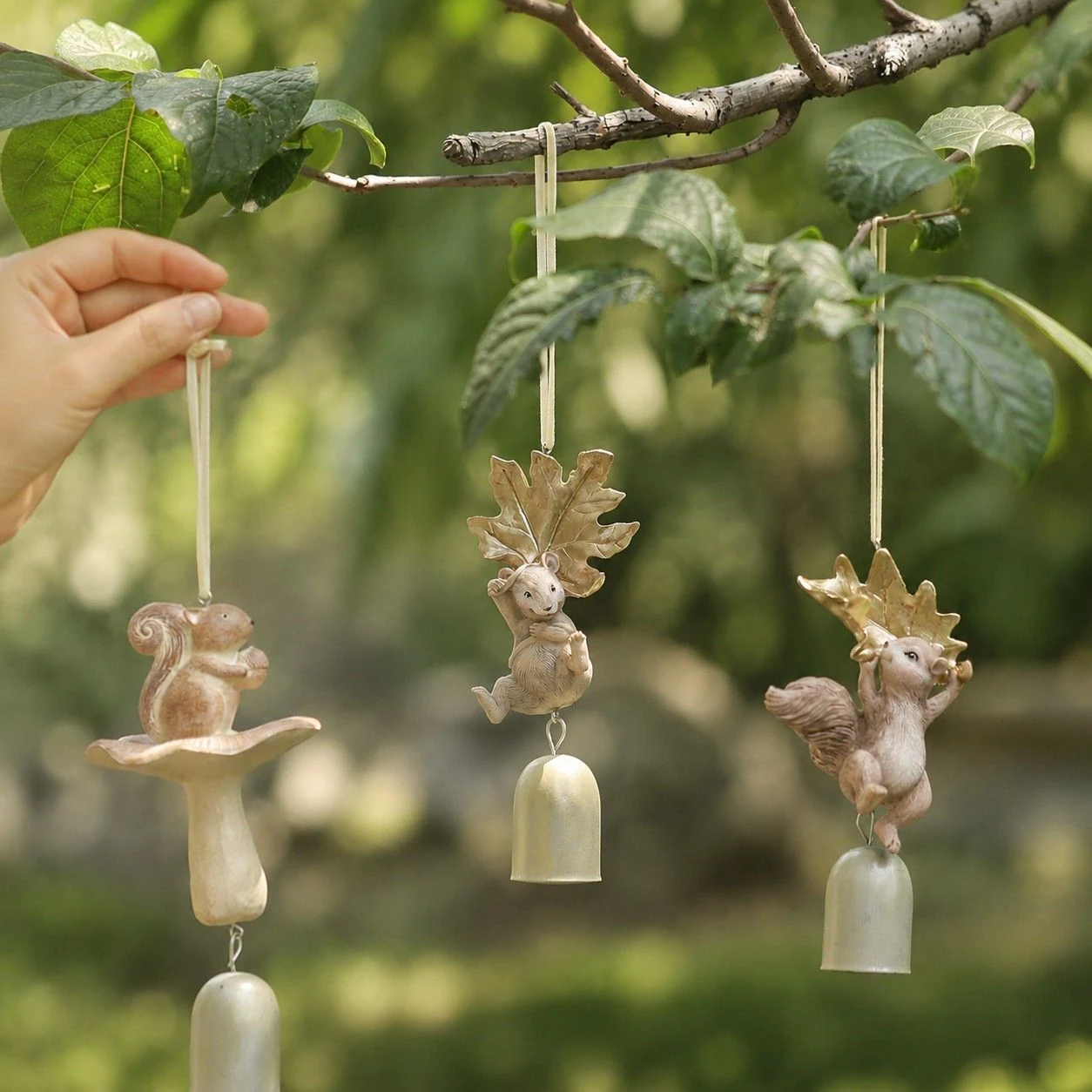 Three warm ivory woodland wind chime styles hanging on a branch